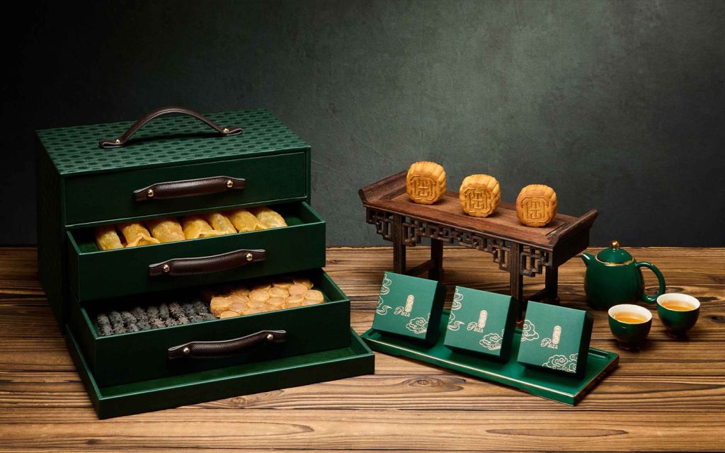 A deep-green chest of leather-handled drawers, built more like luggage than packaging, holding dried seafood delicacies alongside the mooncakes